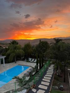 a pool with a sunset in the background at Morad Haharbel - Boutique Resort in Arbel
