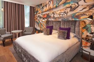 a bedroom with a large bed with purple pillows at Malmaison London in London