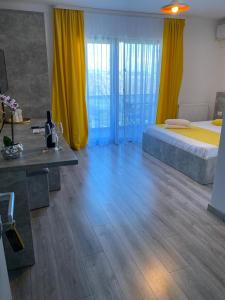 een slaapkamer met een bed met gele gordijnen en een houten vloer bij MAV Boutique Villa in Eforie Nord