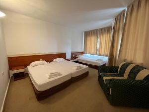 a hotel room with two beds and a couch at Апарт Хотел Мари in Ravda
