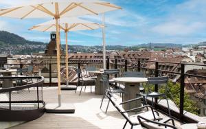 un patio con mesas, sillas y sombrillas en Stay KooooK Bern City - Online Check In, en Berna