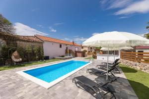 a swimming pool with an umbrella and chairs and a house at Villa Meri in Gabonjin