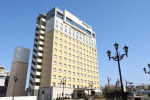 een hoog wit gebouw met een straatlicht ervoor bij Dormy Inn PREMIUM Kushiro in Kushiro