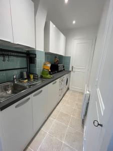 a kitchen with white cabinets and a sink and a stove at Apartment near Montmartre(2 rooms!) in Paris