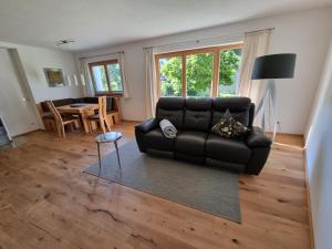 ein Wohnzimmer mit einem schwarzen Sofa und einem Tisch in der Unterkunft Ferienwohnungen Strass im Zillertal in Strass im Zillertal