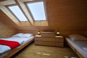 two beds in a wooden room with two windows at Domki Nadmorski Skarb Ostrowo k/Karwi in Ostrowo