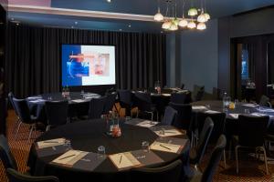 una sala conferenze con tavoli, sedie e schermo di Malmaison London a Londra
