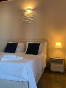 um quarto com uma cama com lençóis brancos e um candeeiro em Spiaggia Le Dune Residence em Margherita di Savoia