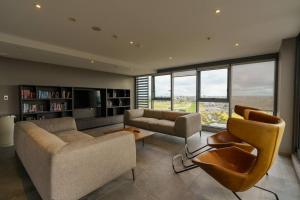 a living room with a couch and chairs and windows at Modern 1 Bed Opposite Racecourse in Melbourne