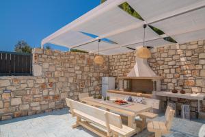 Le Mar Villa في فاسيليكوس: مطبخ خارجي بجدار حجري ومظلة بيضاء