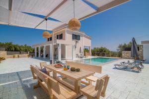 a patio with a table and chairs and a pool at Le Mar Villa in Vasilikos