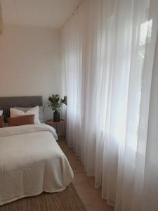 een slaapkamer met witte gordijnen en een groot bed bij Self check in apartment with terrace in Pärnu