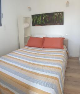 1 cama con almohadas de color naranja y manta a rayas en L'Annexe, en Sigean