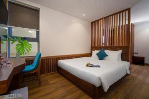 a bedroom with a bed and a desk and a chair at Sea Wind Hotel by THG in Da Nang