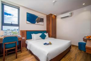 a hotel room with a bed and a desk and a window at Sea Wind Hotel by THG in Danang