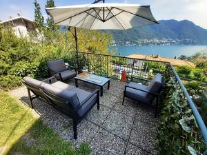 un patio con sillas, una mesa y una sombrilla en La Dolce Vista by My Home In Como, en Moltrasio
