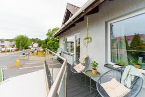 einen Balkon mit Stühlen, einem Tisch und einem Fenster in der Unterkunft Apartamenty Lighthouse - Premium Dźwirzyno in Dźwirzyno