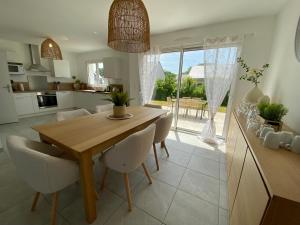 a kitchen and dining room with a wooden table and chairs at Les Voiles Blanches - Accès plage & centrale - Calme et Tranquillité in Brétigny