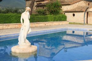 una statua di una donna in piedi accanto a una piscina di Palombara Country House a Montecchio