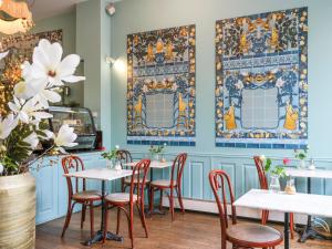 un restaurant avec des tables et des chaises blanches et des murs bleus dans l'établissement 't Hotel, à Amsterdam