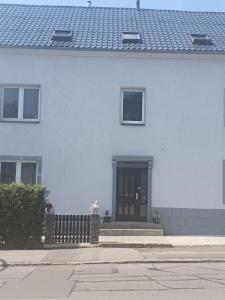 a white house with a black door and a fence at Pension Valentina in Mühlau