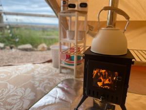 a stove with a tea kettle on top of it at Top pen y parc farm bell tent in Halkyn