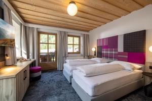 a bedroom with two beds in a room with wooden ceilings at Kinder- & Gletscherhotel Hintertuxerhof in Tux