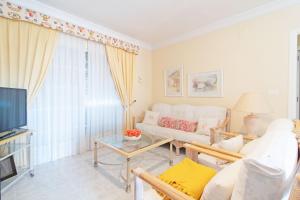 uma sala de estar com um sofá branco e uma televisão em Global Properties, Acogedor adosado en la playa de Corinto em Sagunto