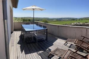 een tafel en stoelen op een terras met een paraplu bij Le panorama des Hautes-Côtes in Fussey