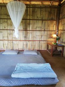 Habitación con cama en una cabaña de paja en La Villa Hortensia-Mondulkiri en Phumĭ Pu Pal