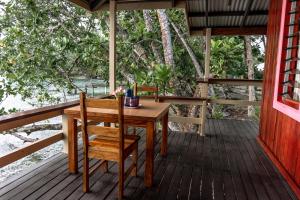 einen Holztisch und einen Stuhl auf einer Veranda in der Unterkunft Leleana Resort Kolombangara Island 