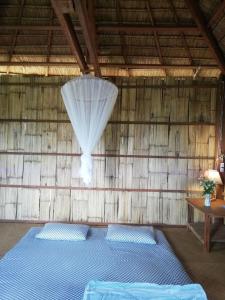 a bedroom with a blue bed in a wooden wall at La Villa Hortensia-Mondulkiri in Phumĭ Pu Pal