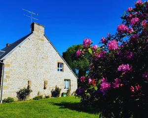 an old stone church with pink flowers in front of it at Maison en pierre au milieu du bocage in Coulouvray-Boisbenâtre