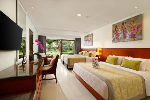 a hotel room with two beds and a desk at Bali Dynasty Resort in Kuta