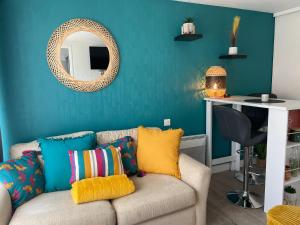 uma sala de estar com um sofá com almofadas coloridas em LE GAUGUIN, T2 Cosy, 2-4 Pers, à 300m des plages em Clohars-Carnoët