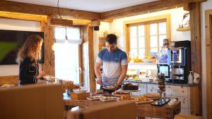 un hombre y una mujer parados en una cocina preparando comida en BB le Fontanelle, en Carano