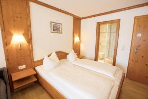 a bedroom with a large white bed with a mirror at Alpenrose Appartements in Nesselwang