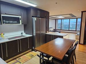a kitchen with a wooden table and a kitchen with a refrigerator at Dongtan Sharp-2 Family House in Hwaseong