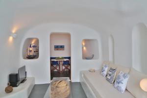 a white living room with a couch and a table at Lava Caves in Oia