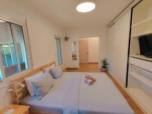 een groot wit bed in een kamer met een raam bij Galilee Best Location in ‘En Dor