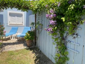 un jardin avec des chaises bleues et une clôture ornée de fleurs violettes dans l'établissement Little Blue House, à Sidari