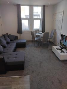 a living room with a couch and a table at Top Quality Modern Southsea Garden Apartment Sleeps 4 People in Portsmouth