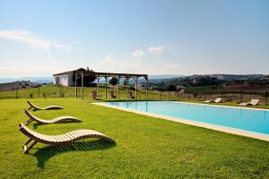 dos bancos de madera sentados en el césped junto a una piscina en Auberge Santu Martine: Cottage with pool (Pira), en Galtellì
