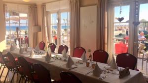 a room with a long table with red chairs at Strandhotel Grömitz in Grömitz