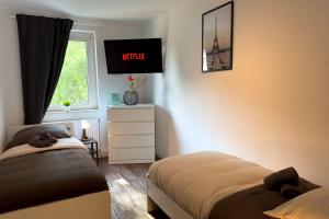 a bedroom with two beds and a tv on the wall at Work & Stay Apartment with Balcony in Osnabrück