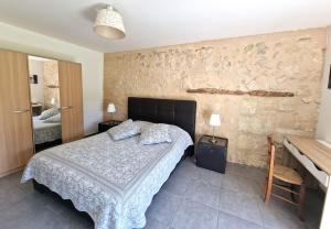 - une chambre avec un lit et un mur en pierre dans l'établissement Le Canteloup, à Saint-Caprais-de-Bordeaux