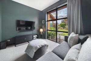 a living room with a couch and a large window at Skye Scape - Jacks Point Retreat in Queenstown
