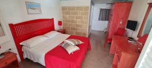a red bed with two pillows on it in a room at Albergo isola mia in Favignana