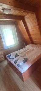 a bed in a wooden room with a window at Domki MEDYK in Jantar