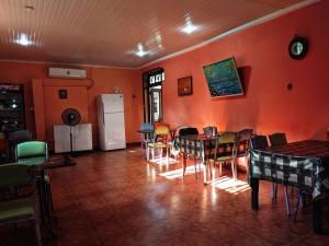 a dining room with orange walls and tables and chairs at Hostel Ureki Kidobani in Ureki